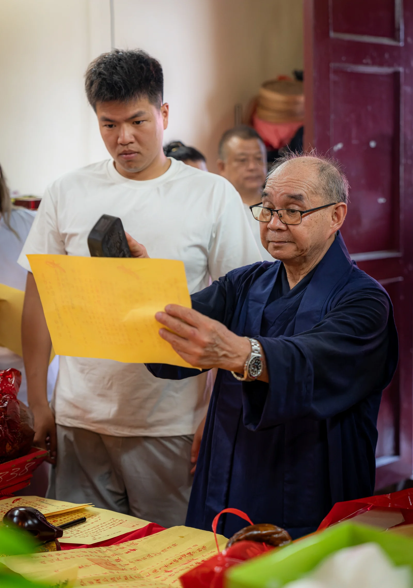 關帝誕期間,師傅手持黃紙誦讀,善信在旁參與